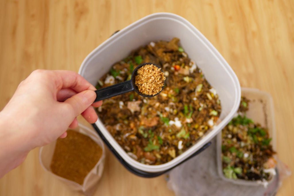 Bokashi bran being added to a full Bokashi compost bin