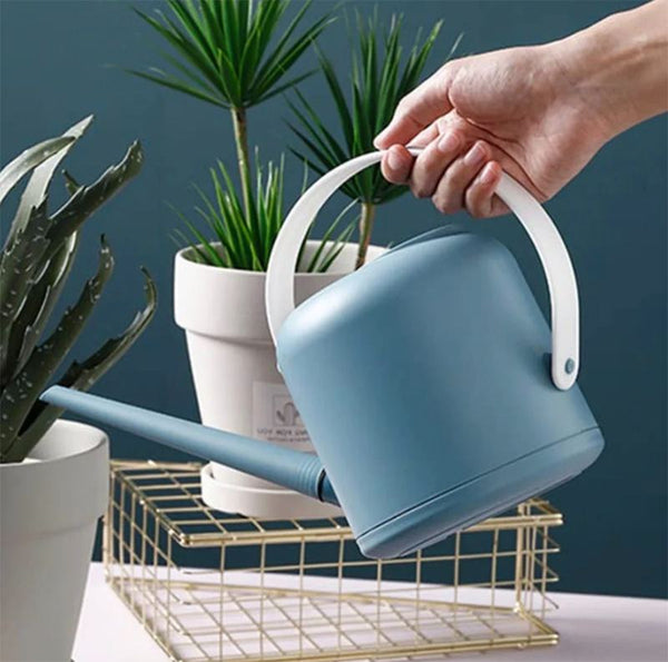 A hand holding a blue watering can