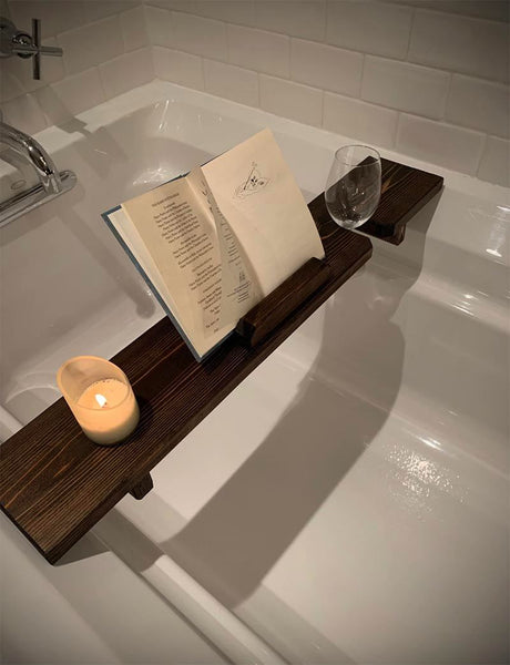 A dark wood tray across a bathtub