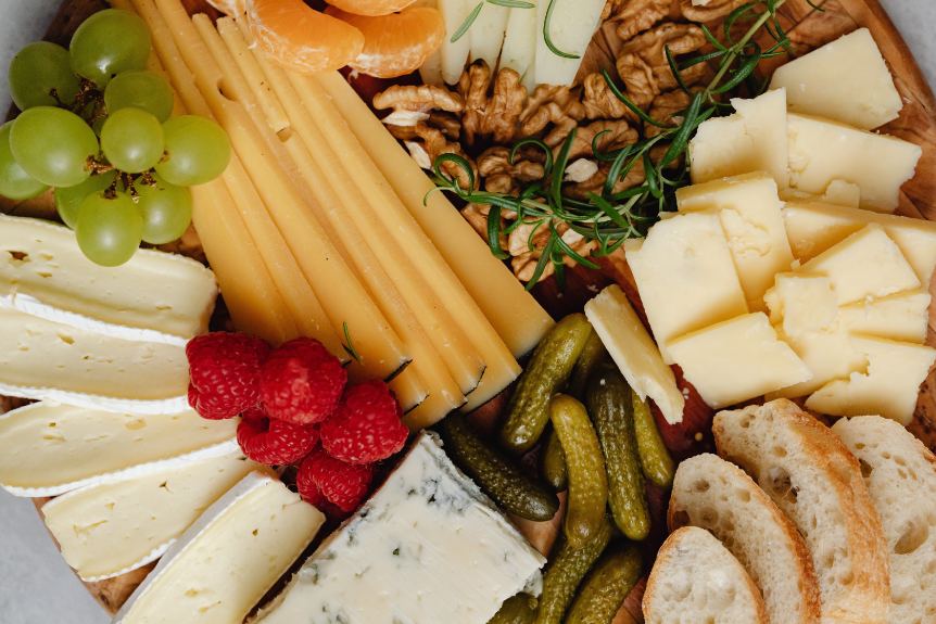 A close up of a charcuterie board filled with cheese and produce
