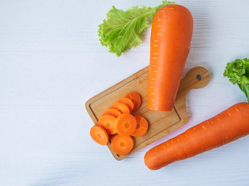 Two large carrots being chopped into smaller circular pieces