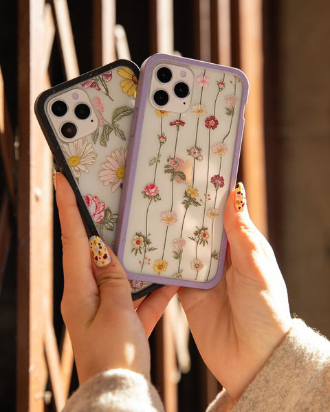 person holding two clear phone cases with floral designs on them