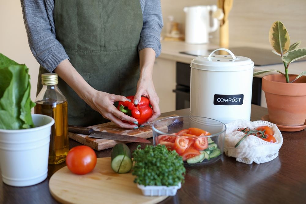 person putting food scraps into a compost bin