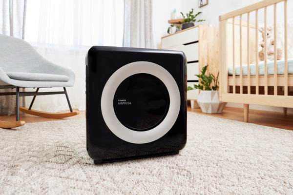 Small black and white air purifier set up on the carpet in a nursery