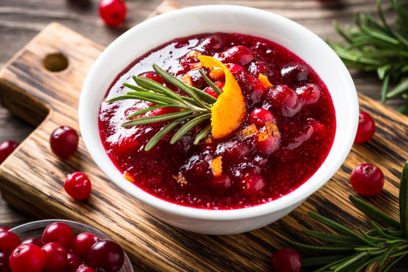 A bowl of cranberry sauce with a lemon peel in it