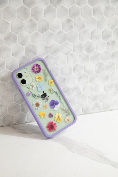 phone case that looks like it has pressed flowers in it leaned against a wall
