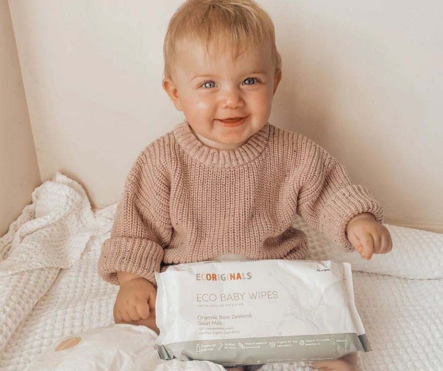 A baby holding a container of baby wipes