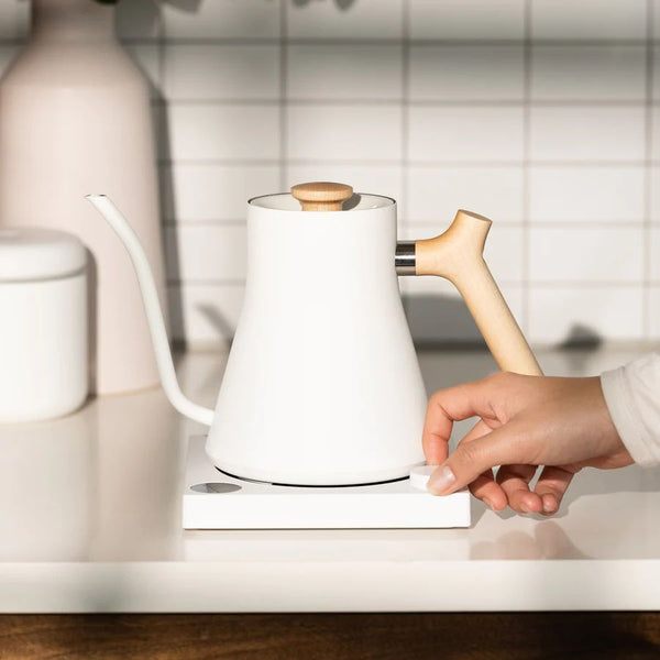 Hand touching white electric kettle