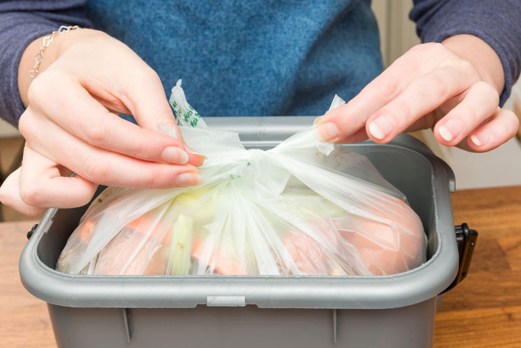 A woman tying up a garbage bag