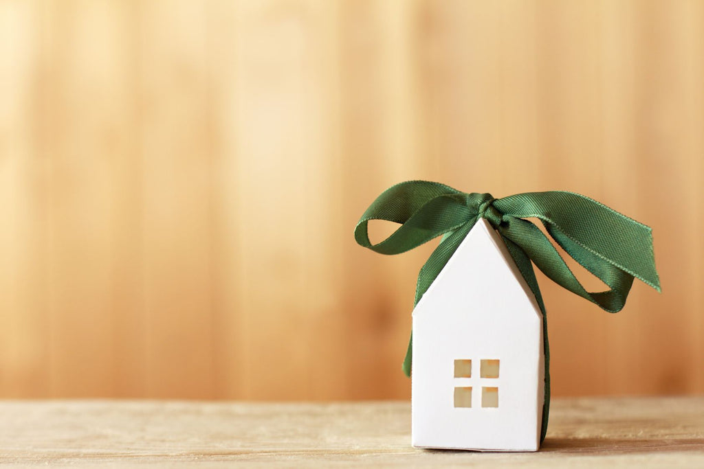 A small paper house wrapped in a green ribbon