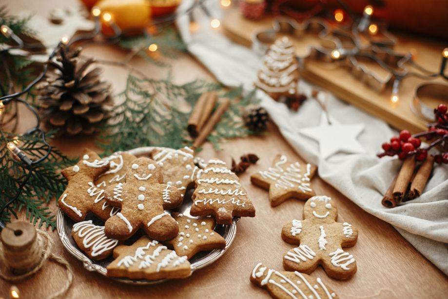 A plate full of holiday gingerbread cookies next to some festive decorations