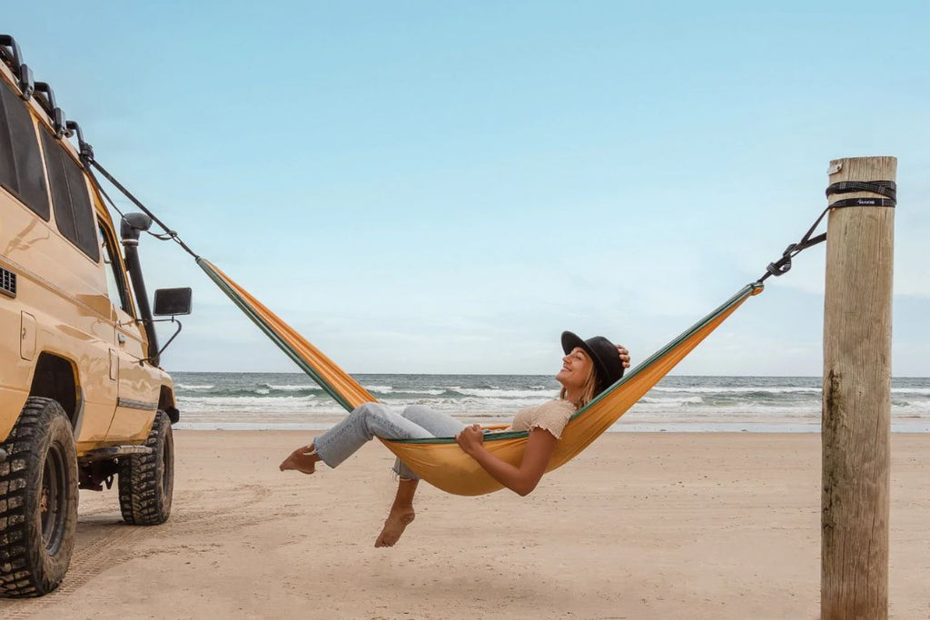 A young woman swinging in a golden mango hammock
