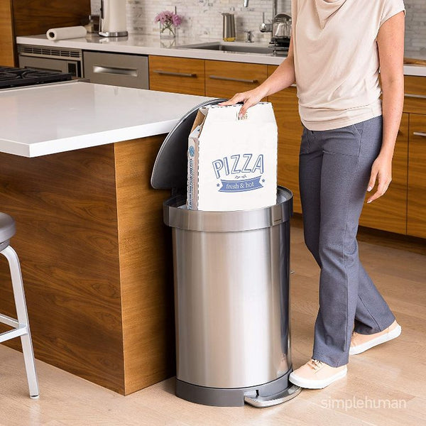 person putting a pizza box into a metal steel trash can