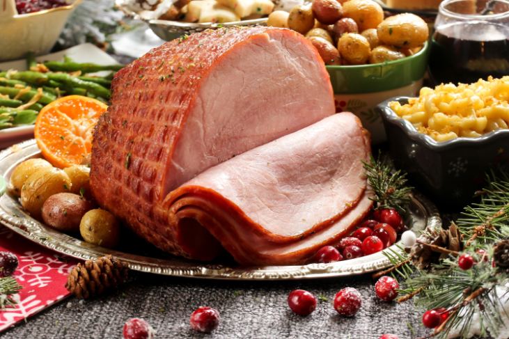 A partially-sliced roast ham on a festive dining table