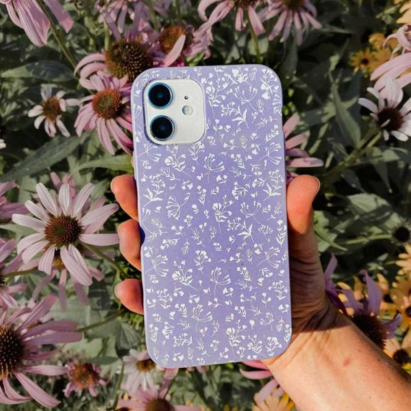 person holding a purple phone case with engraved flower pattern up to the camera