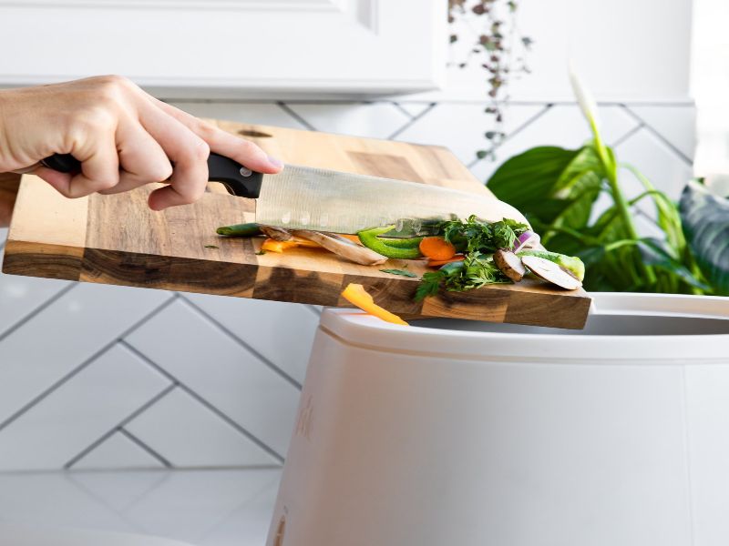 A woman adding food scraps to Lomi