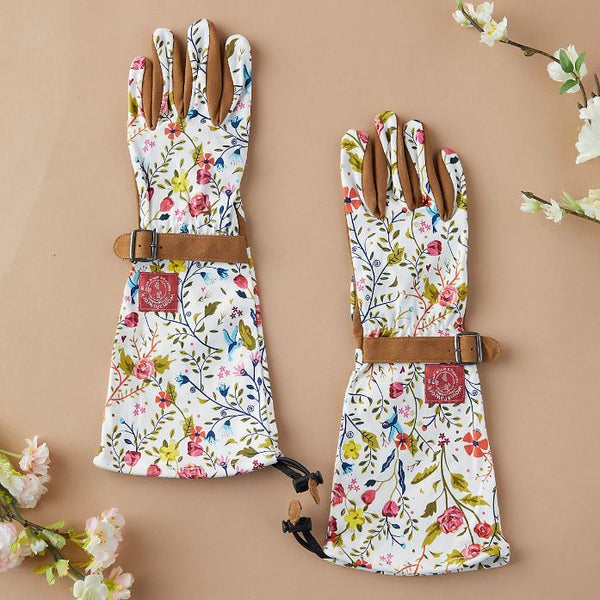 White and floral-patterned garden gloves on a pink background