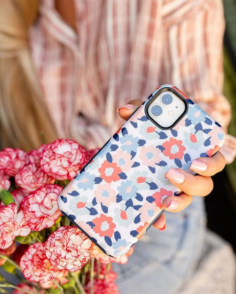 person holding a floral phone case next to some flowers