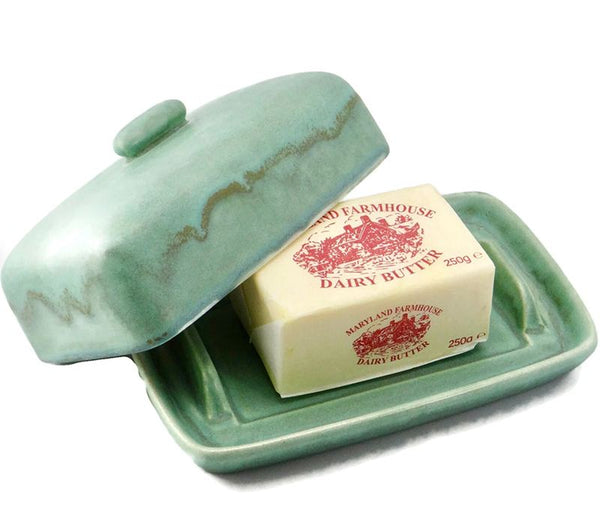 A blue green butter dish on a white background