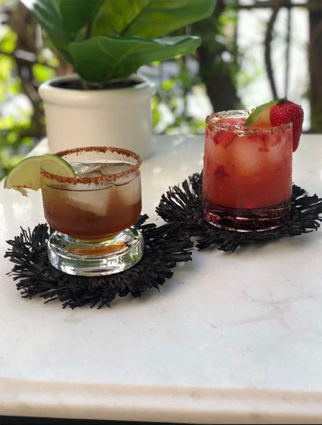 Black fringed coasters under two drinks