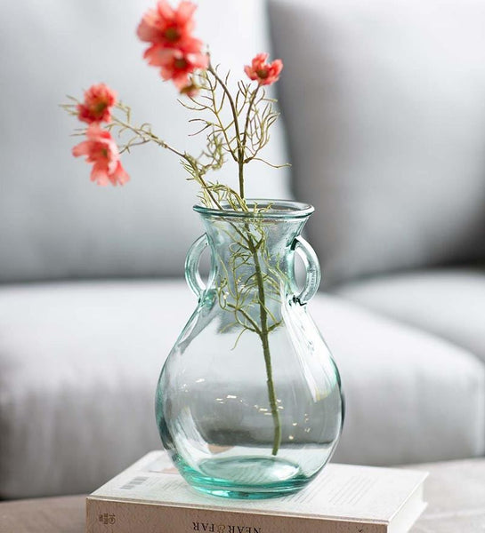 A clear blue vase with pink flowers inside