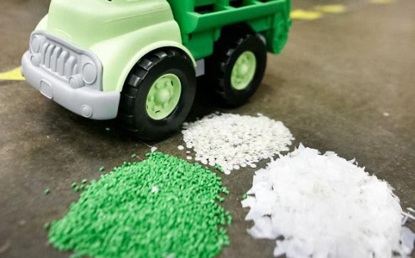 A Green Toys truck next to small piles of recycled plastic