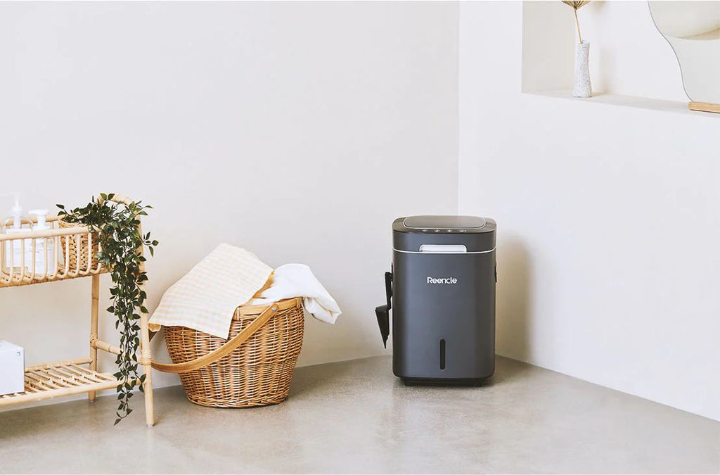 The Reencle compost machine sitting on the floor in the corner of a room