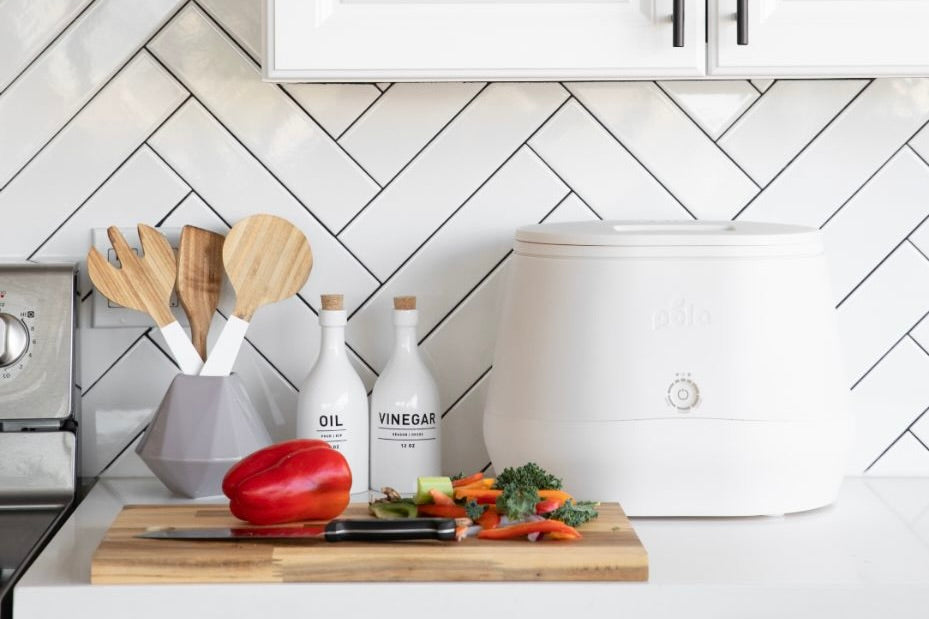 Compost bin on white countertop next to chopped vegetables