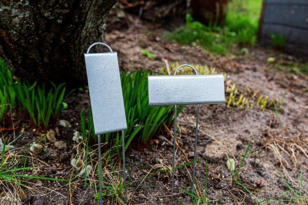 Two blank steel plant markers standing in a garden