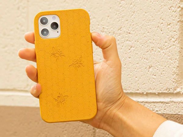 person holding a yellow phone case with bees and a honeycomb pattern engraved on it