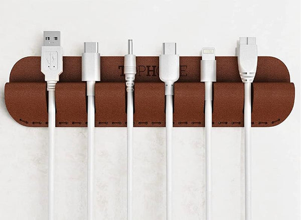 A brown leather cable organizer with white cords hanging from it