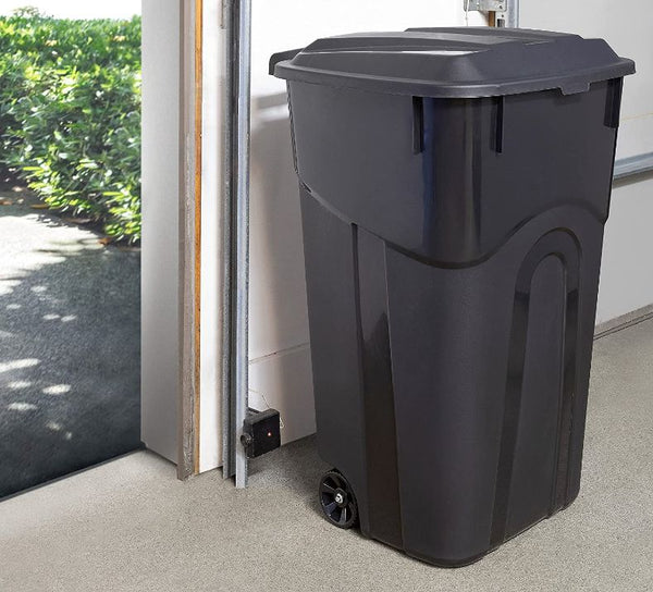 a black trash can sitting next to an open garage door