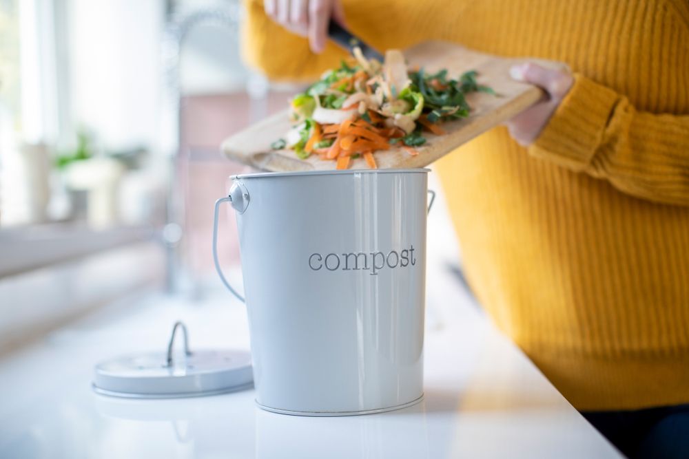 Person scraping vegetable peels into an indoor bin