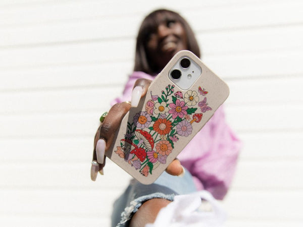 woman holding a phone case with smiling mushrooms and flowers