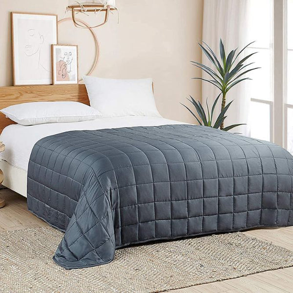 A blue gray quilted blanket on a bed