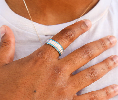 hand wearing transgender pride ring flat on her chest