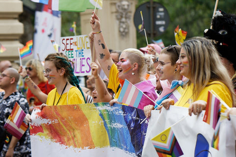 Lgbt pride parade outdoors people holding pride flags and signs wearing rainbow clothing