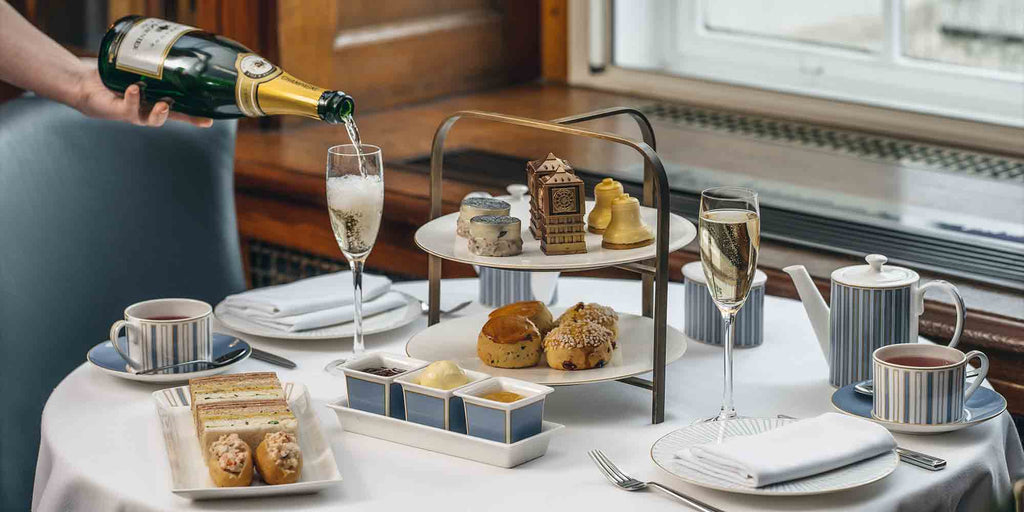 Luxury hotel Afternoon Tea set up on white table cloth in luxury hotel. Cakes and ginger sandwiches on tiered platters.