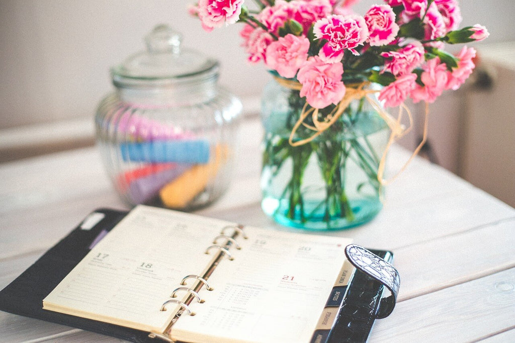 daily planner open in front of flowers in vase