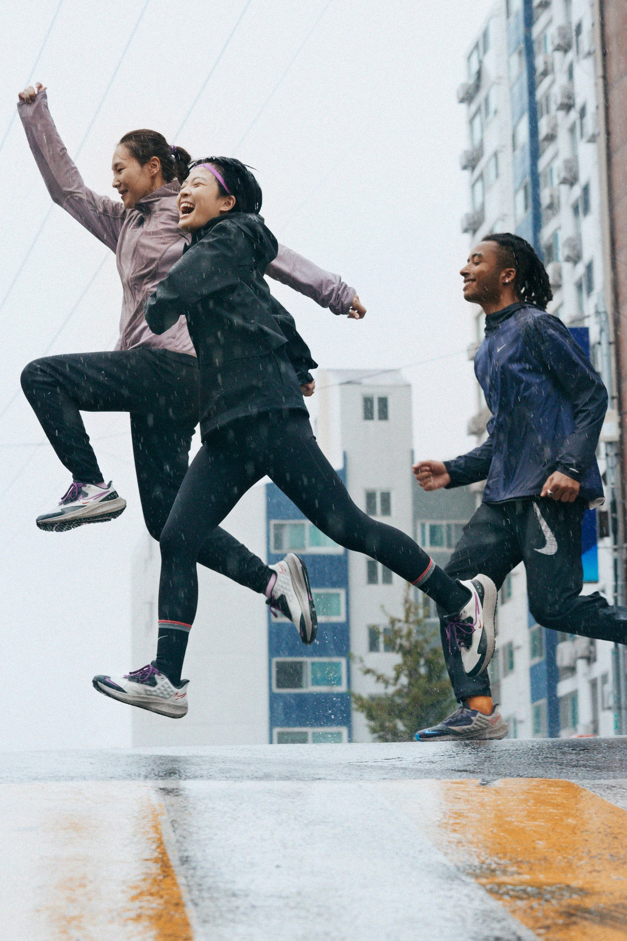 Three runners crossing pedestrian crossing in the rain