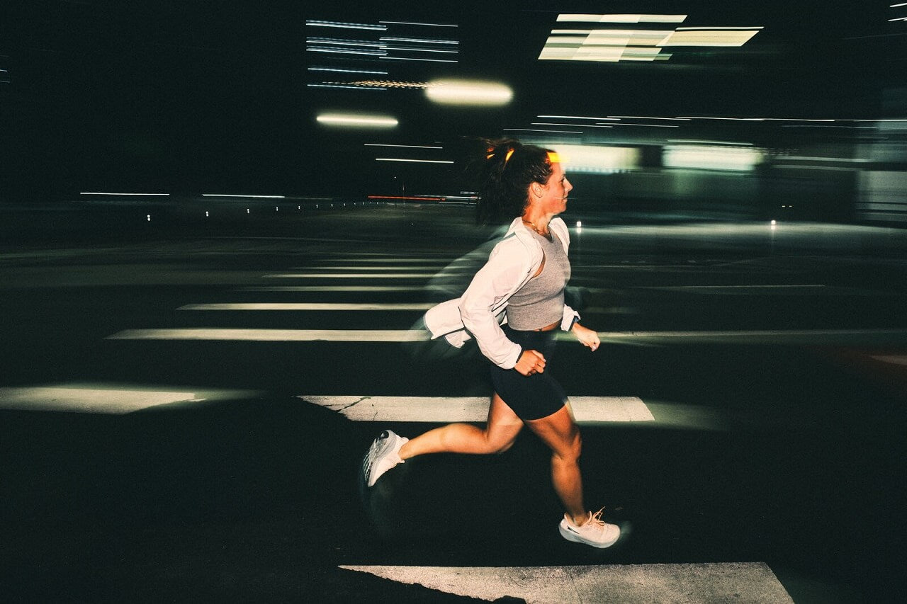 Woman running in the dark in street lights