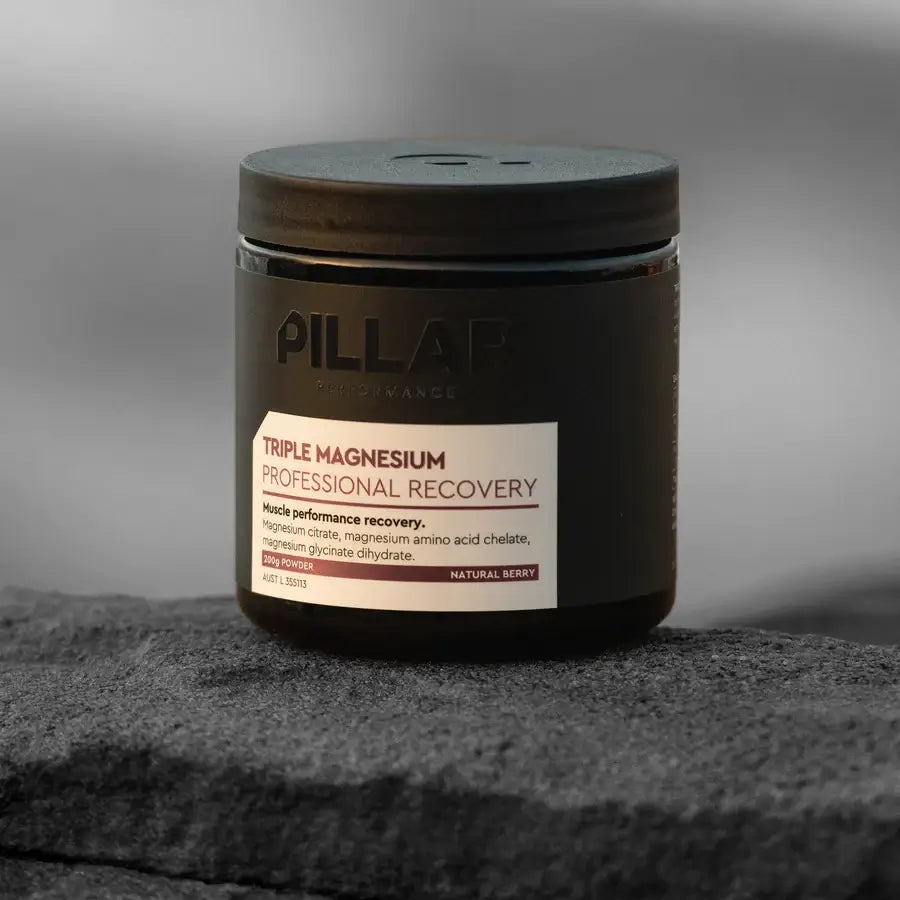 Glass jar of PILLAR Performance Triple Magnesium Professional Recovery Powder sitting on dark granite stone