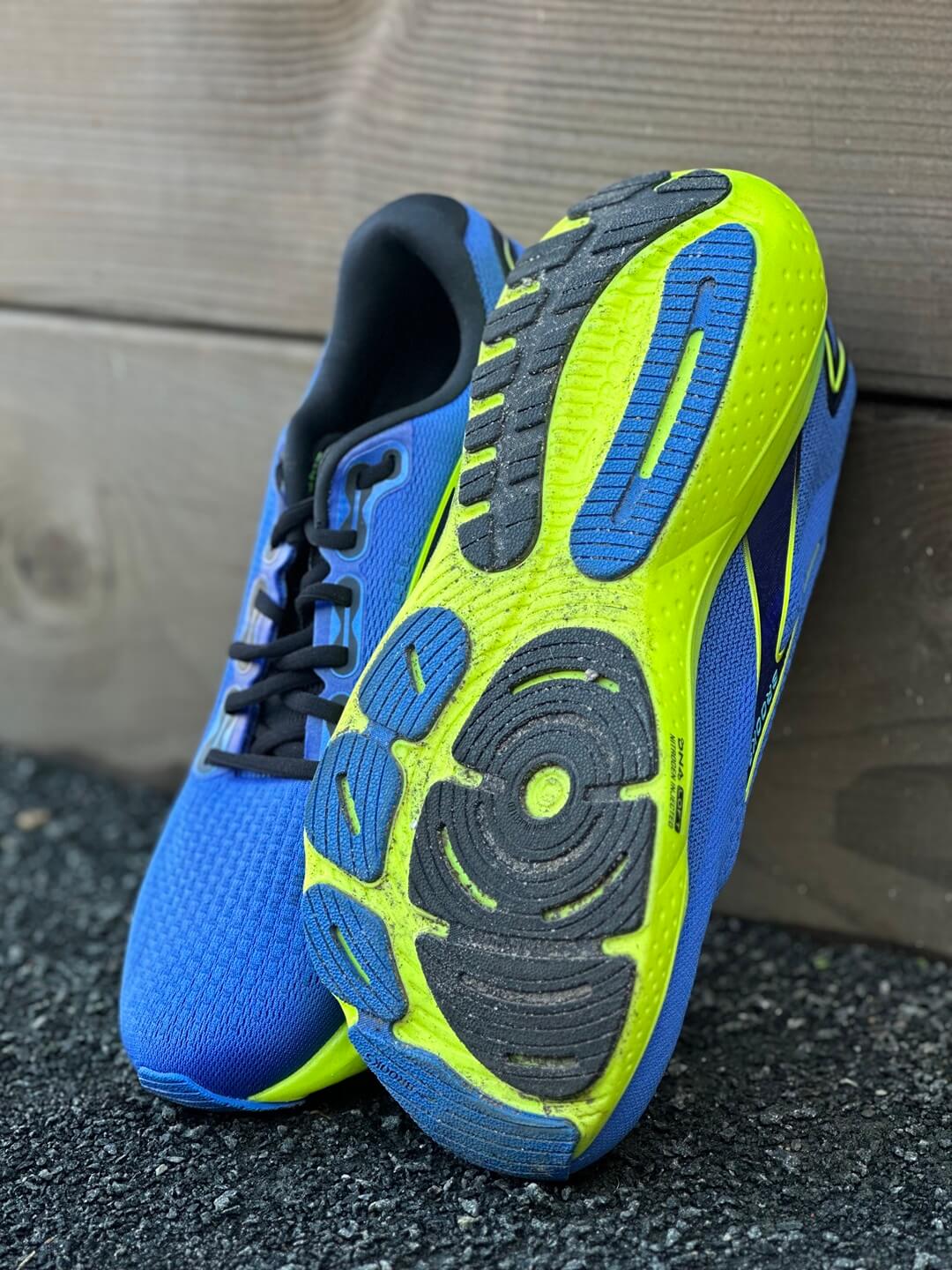 Pair of blue Brooks Glycerin 21 running shoes propped against a wall. One shoe flipped over to reveal the outsole.