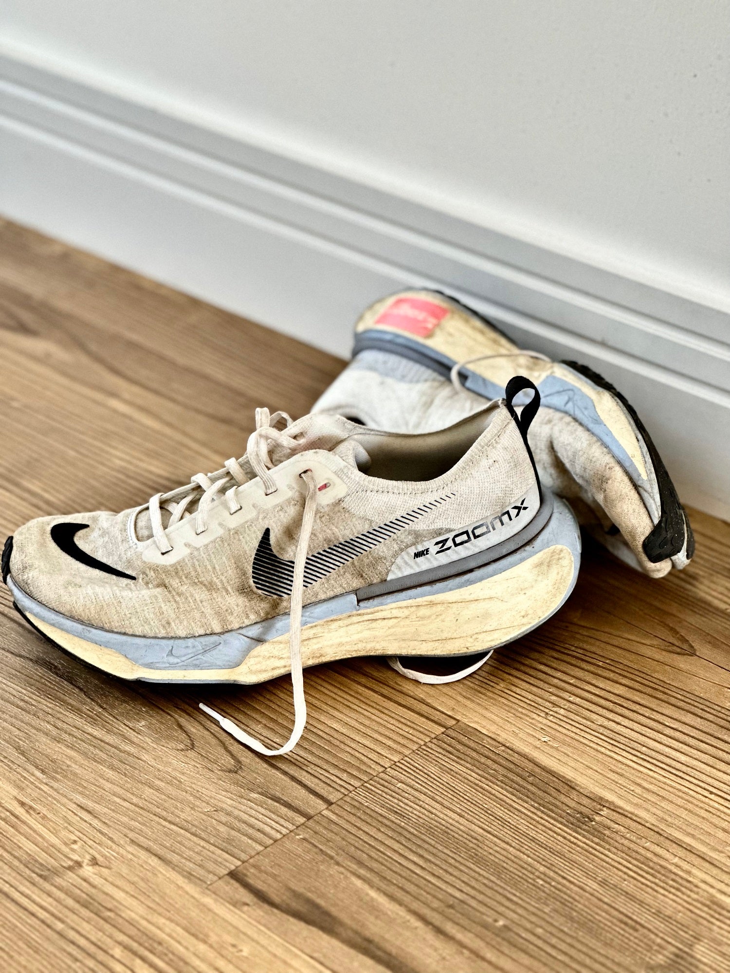 Worn pair of Nike Invincible Run running shoes on wooden floor