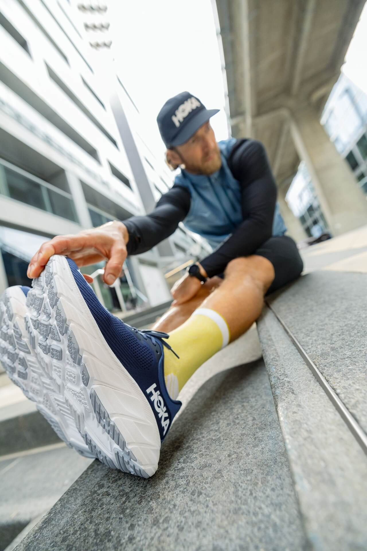 Male runner stretching in HOKA running shoes