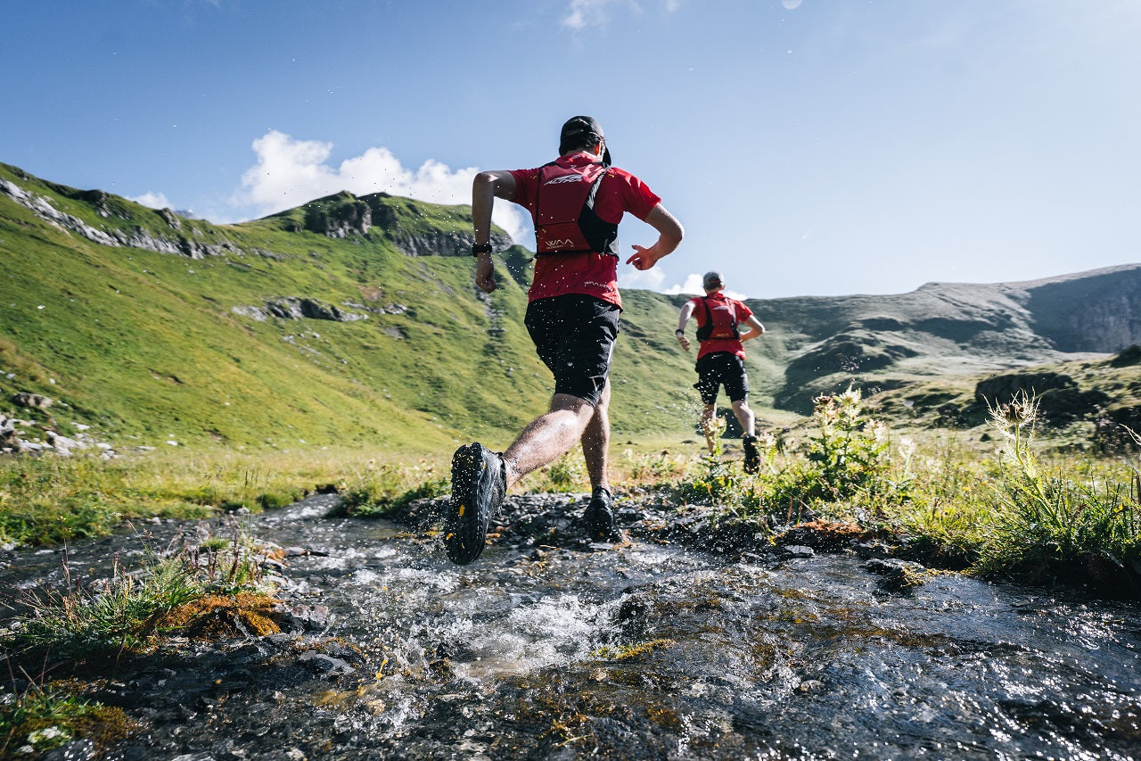 Two men running across a burn in the mountains