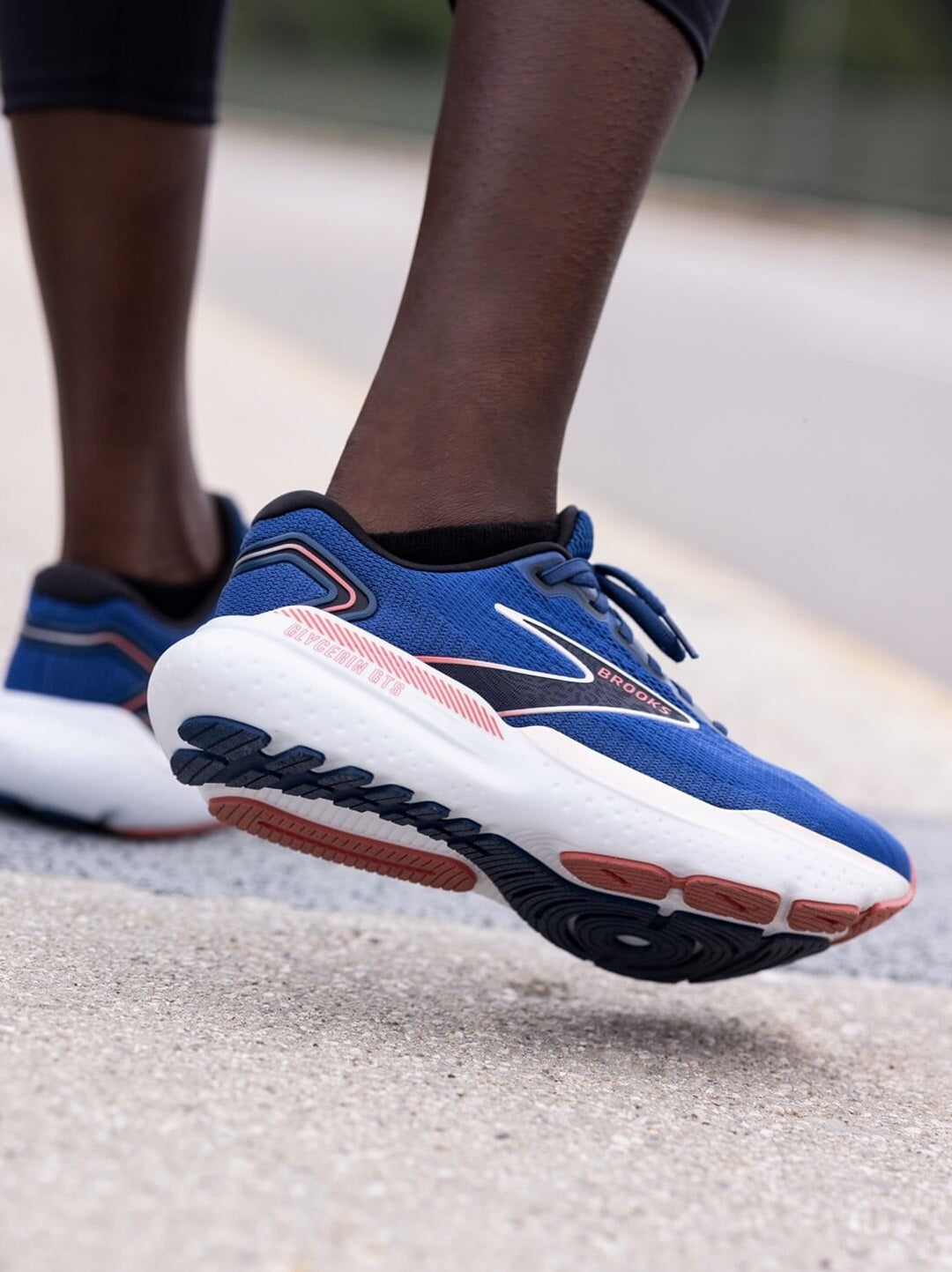 Runner standing in Brooks running shoes with right leg raised and tilting inward