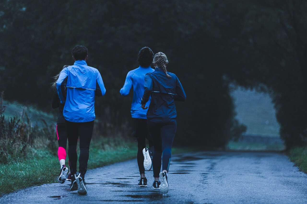 Group of runners running along a country road in wet conditions