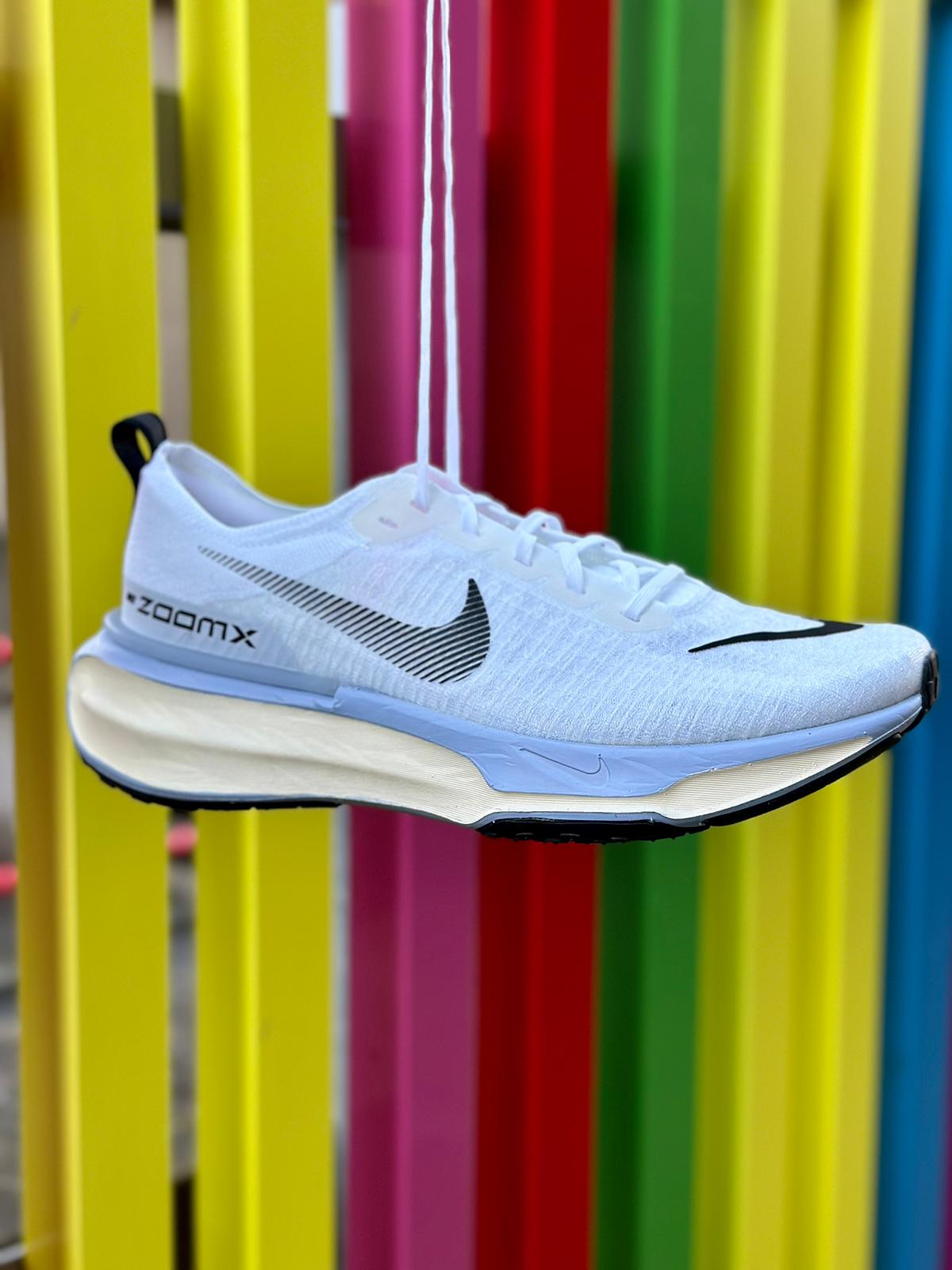 Nike ZoomX Invincible Run 3 running shoe hanging in the air against a rainbow striped gate