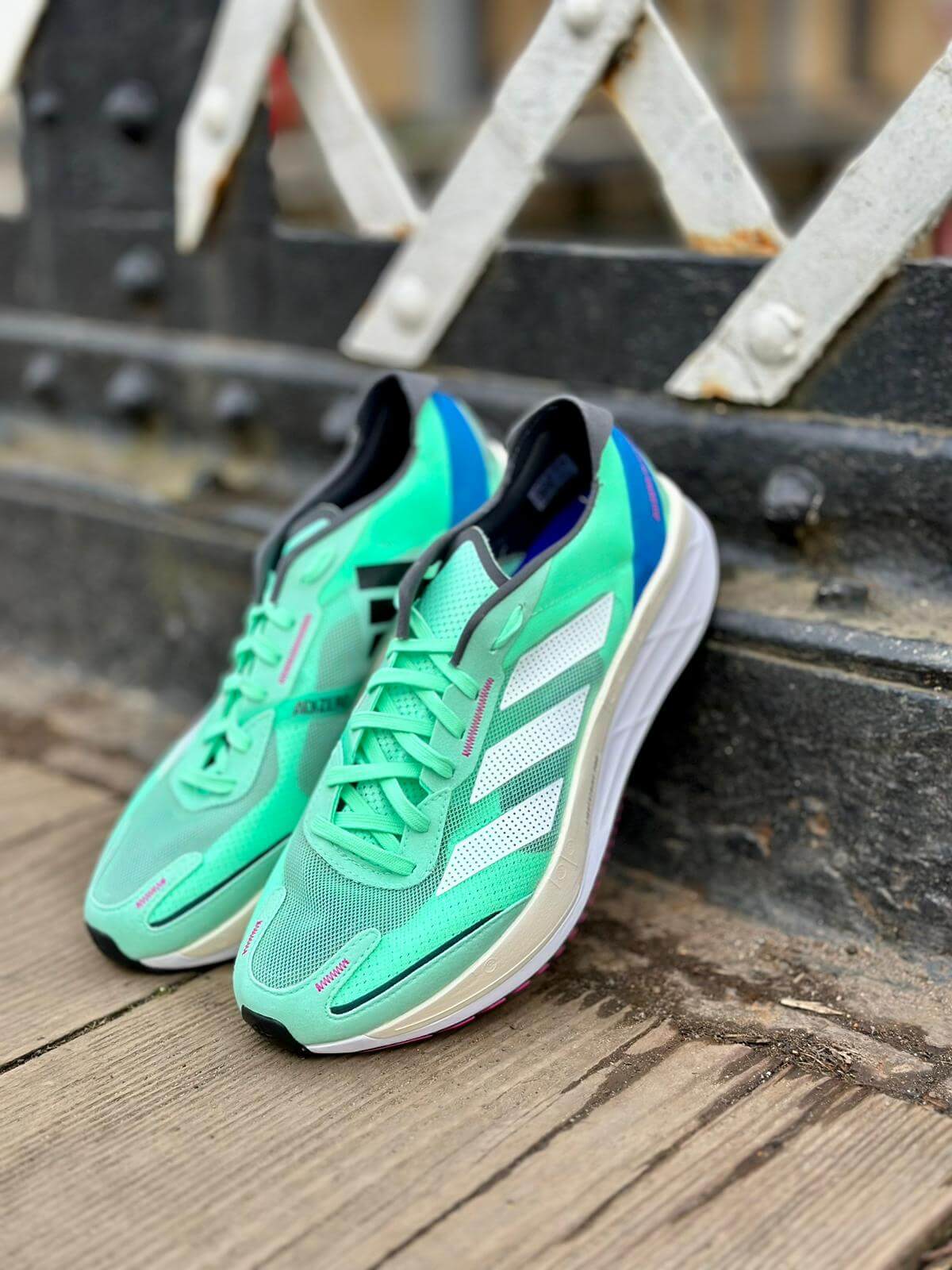 Pair of adidas Adizero Boston 11 running shoes in Pulse Mint colourway propped on bridge